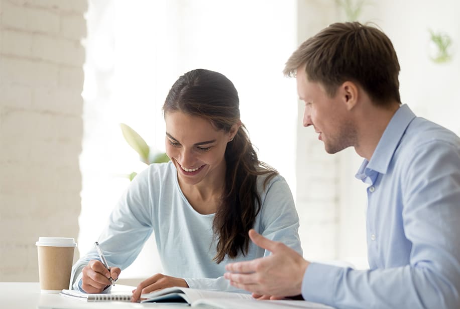 Woman taking notes while man talks.